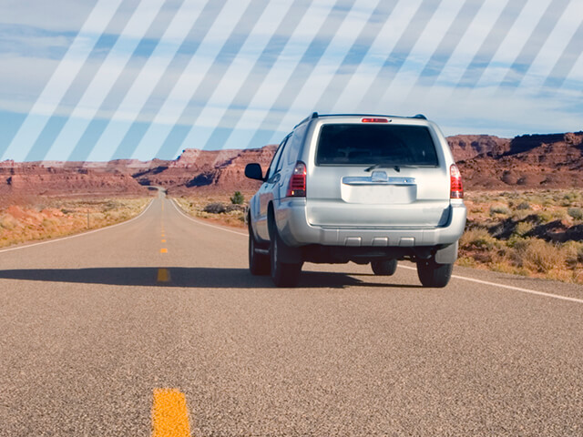 A Toyota SUV on a lonely road out west. 
