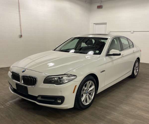 A used white 2016 BMW 5 series in a dealer photo room
