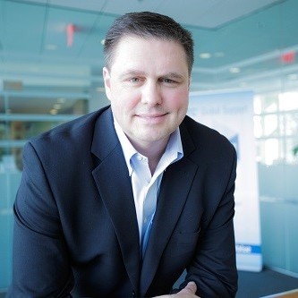 Tim Fox, ACV's Chief Financial Officer, smiles at the camera in a white button down shirt and black blazer.
