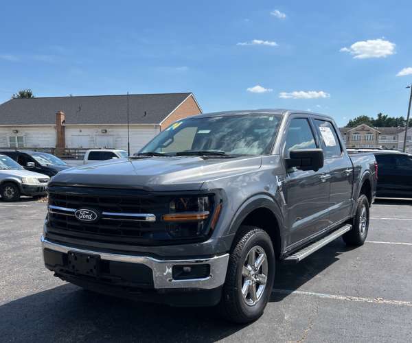 A black Ford F-150 Truck in a crowded dealer parking lot