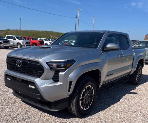 A red Toyota Tacoma in a full dealer parking lot