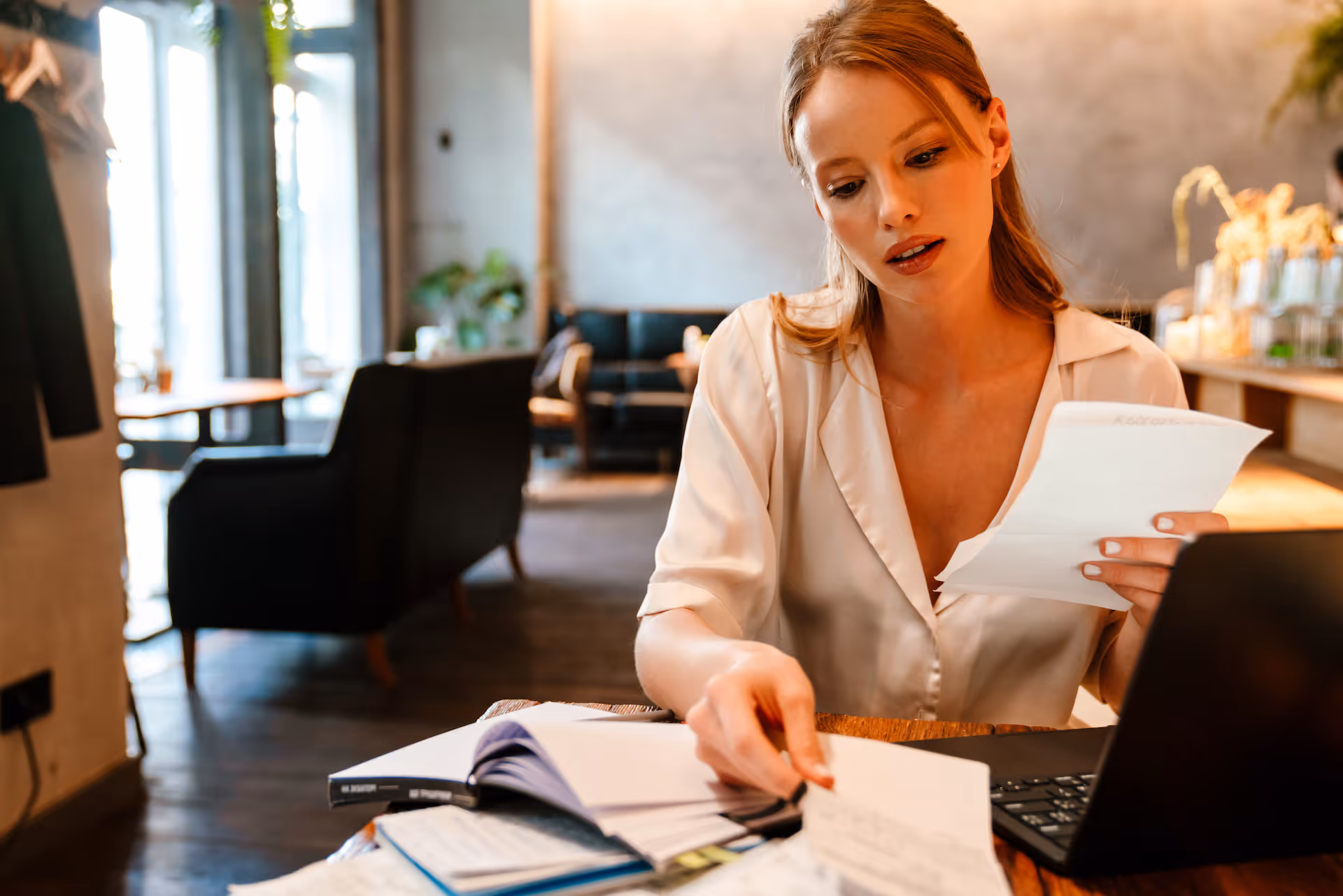Young restaurant manager doing paperwork and using laptop