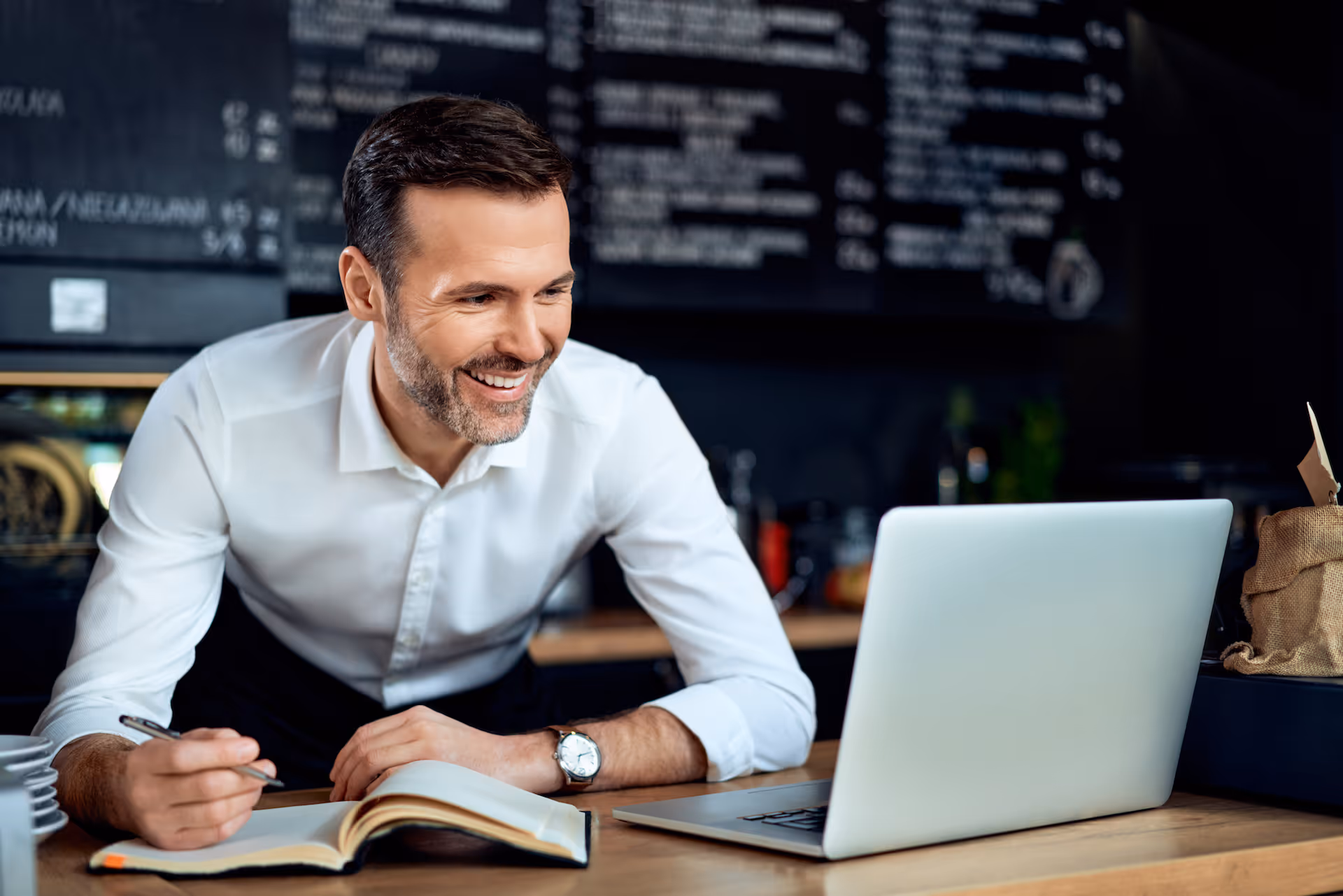 restaurant owner using laptop writing expenses