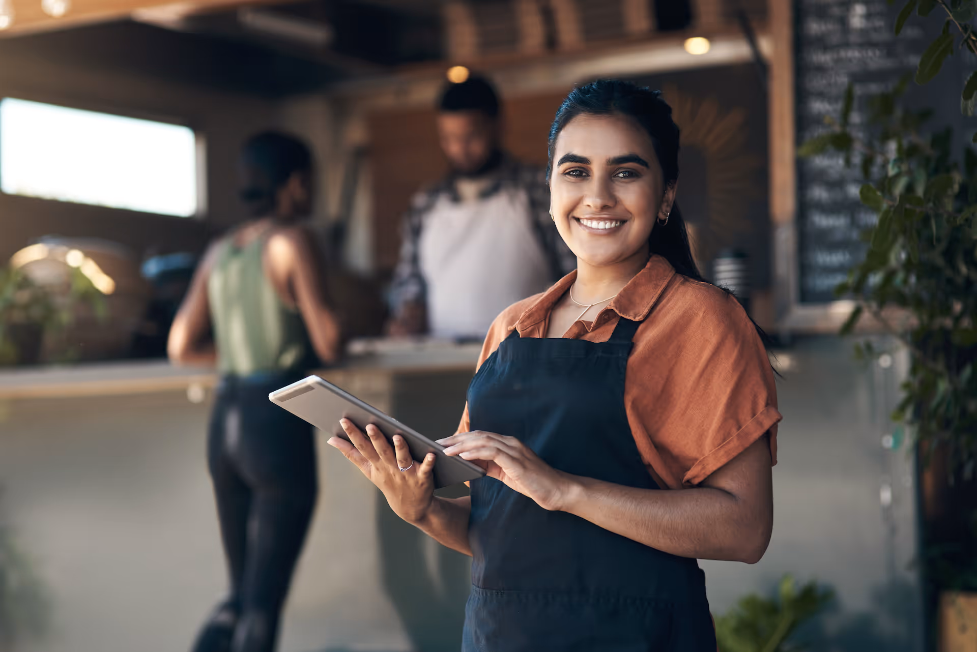 Young woman standing outside her restaurant and using a digital tablet