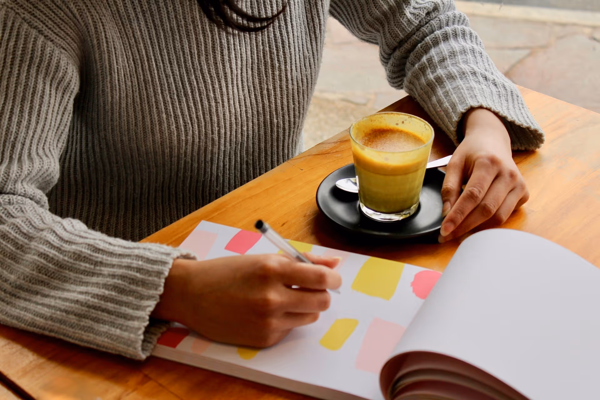 person holding pen with coffee on table