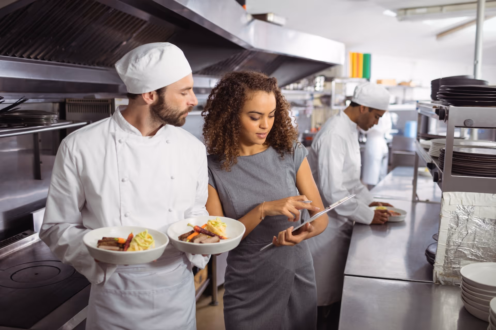Manager discussing menu on clipboard with chef
