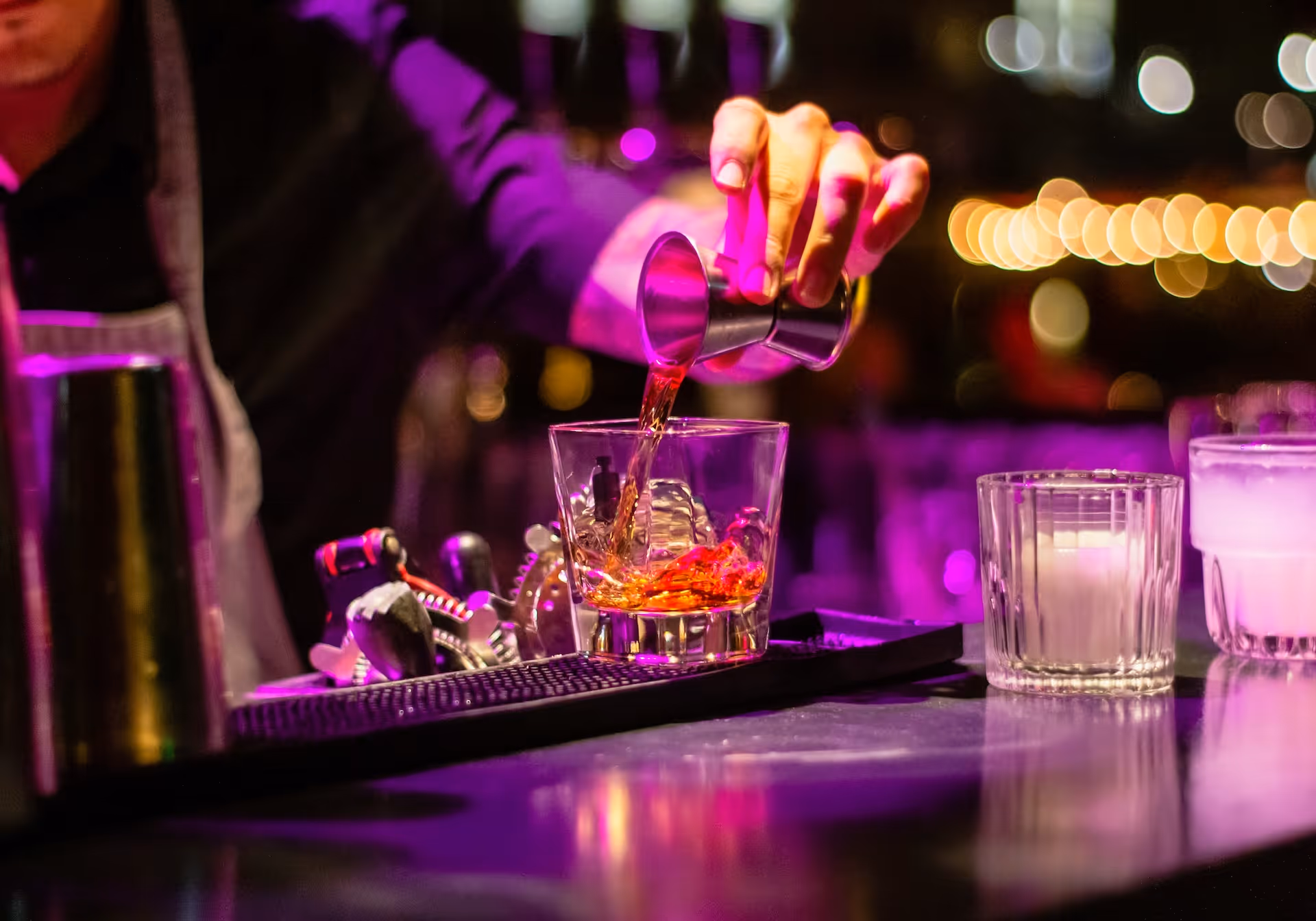 bartender pouring liquor in clear drinking glass