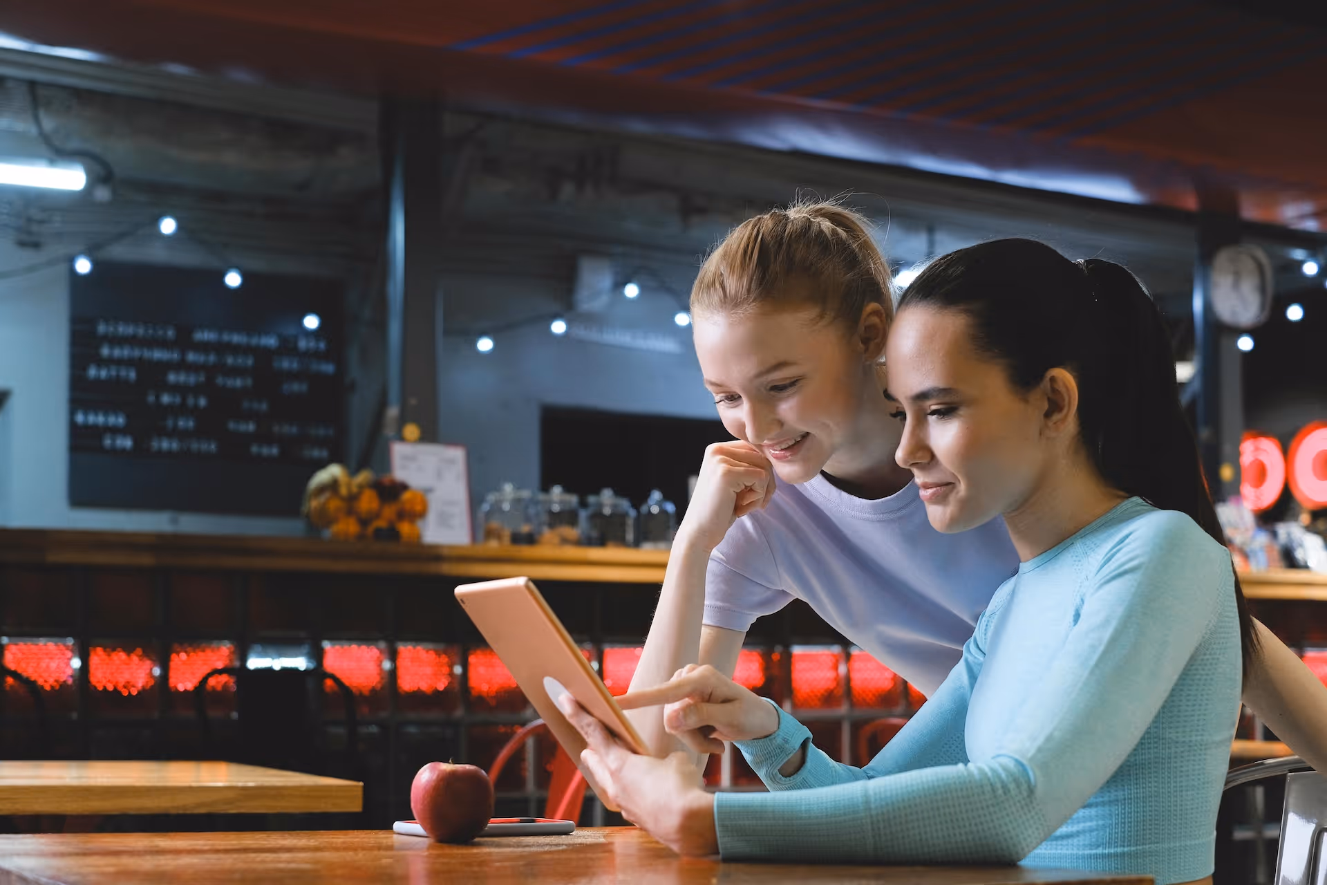 two woman at restaurant looking at tablet
