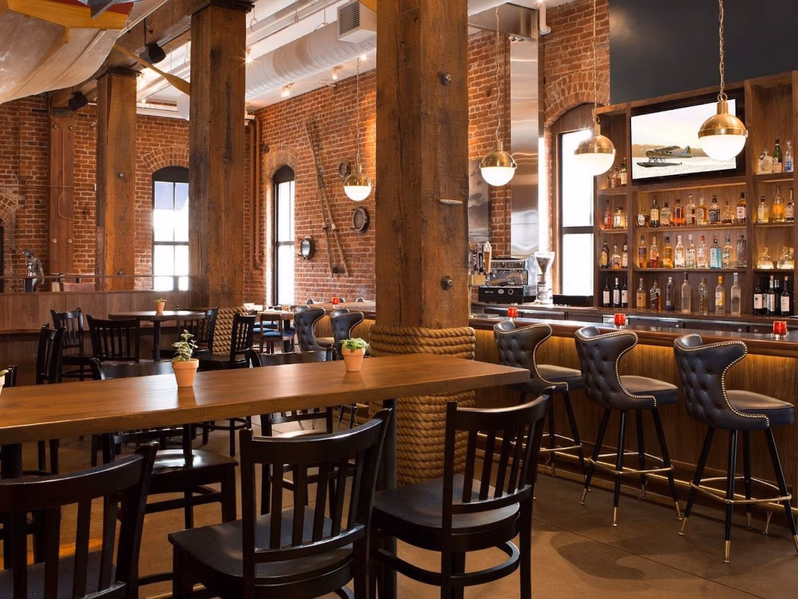view of brick interior, long dining table, and fully-stocked bar at Nari restaurant, San FranciscoB
