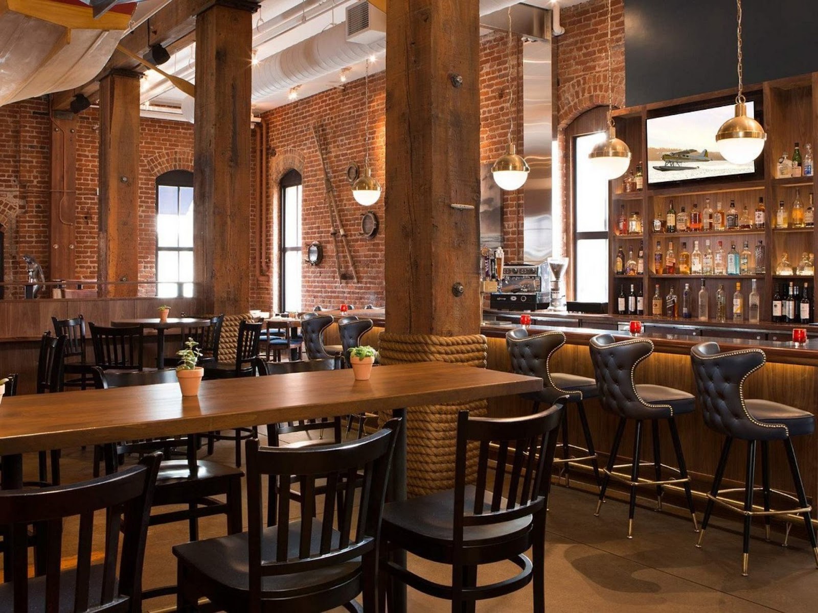 view of brick interior, long dining table, and fully-stocked bar at Nari restaurant, San FranciscoB