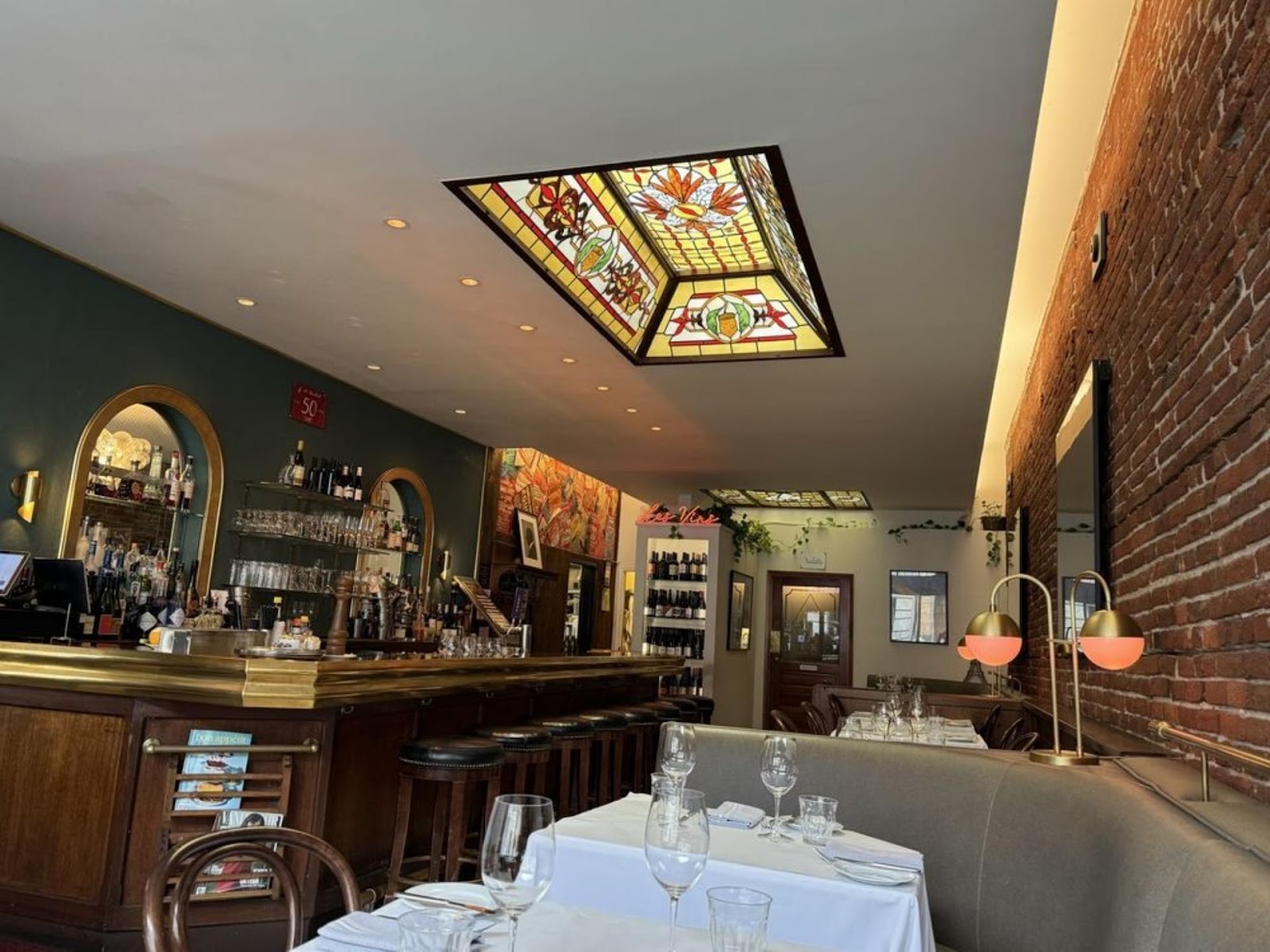 bottom-to-top view of interior dining tables and seating in Le Central restaurant, SF, with a view of painted glass skylight