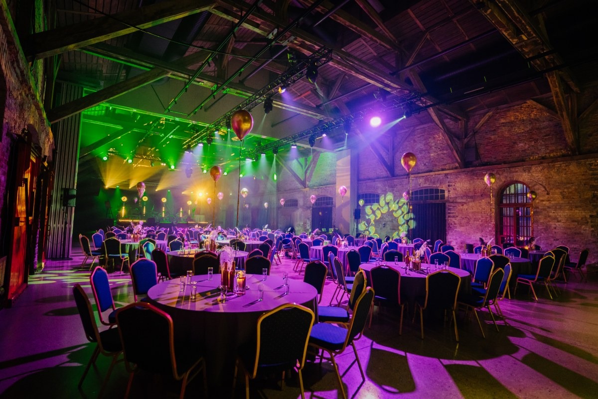 Event set up in large venue with tables and colorful lights