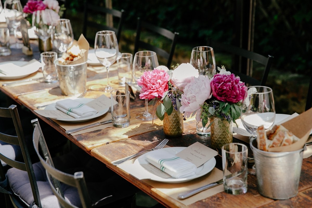 Table set up outdoors with place settings and pink flowers
