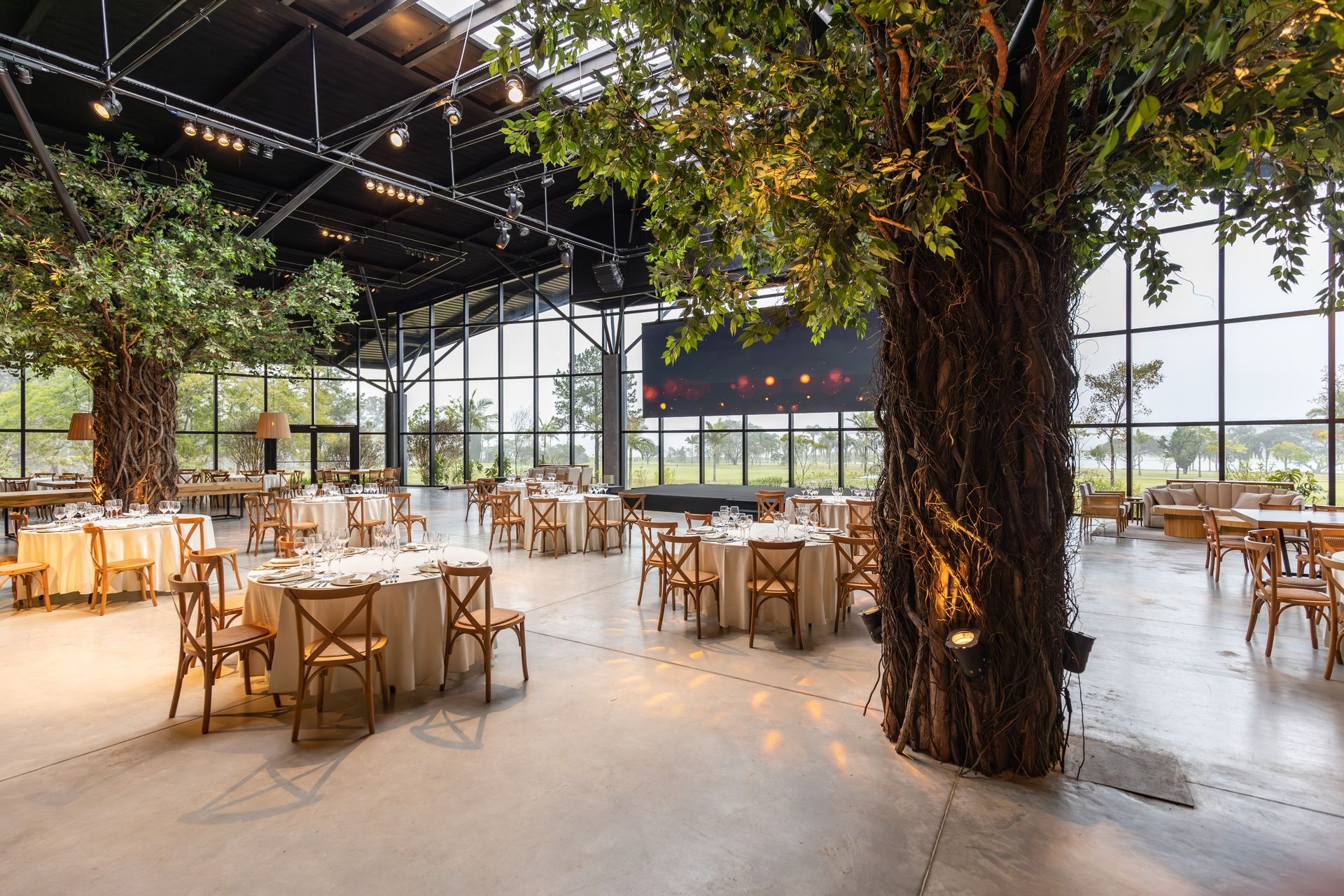beautiful large event venue with trees and glass walls and warm lighting