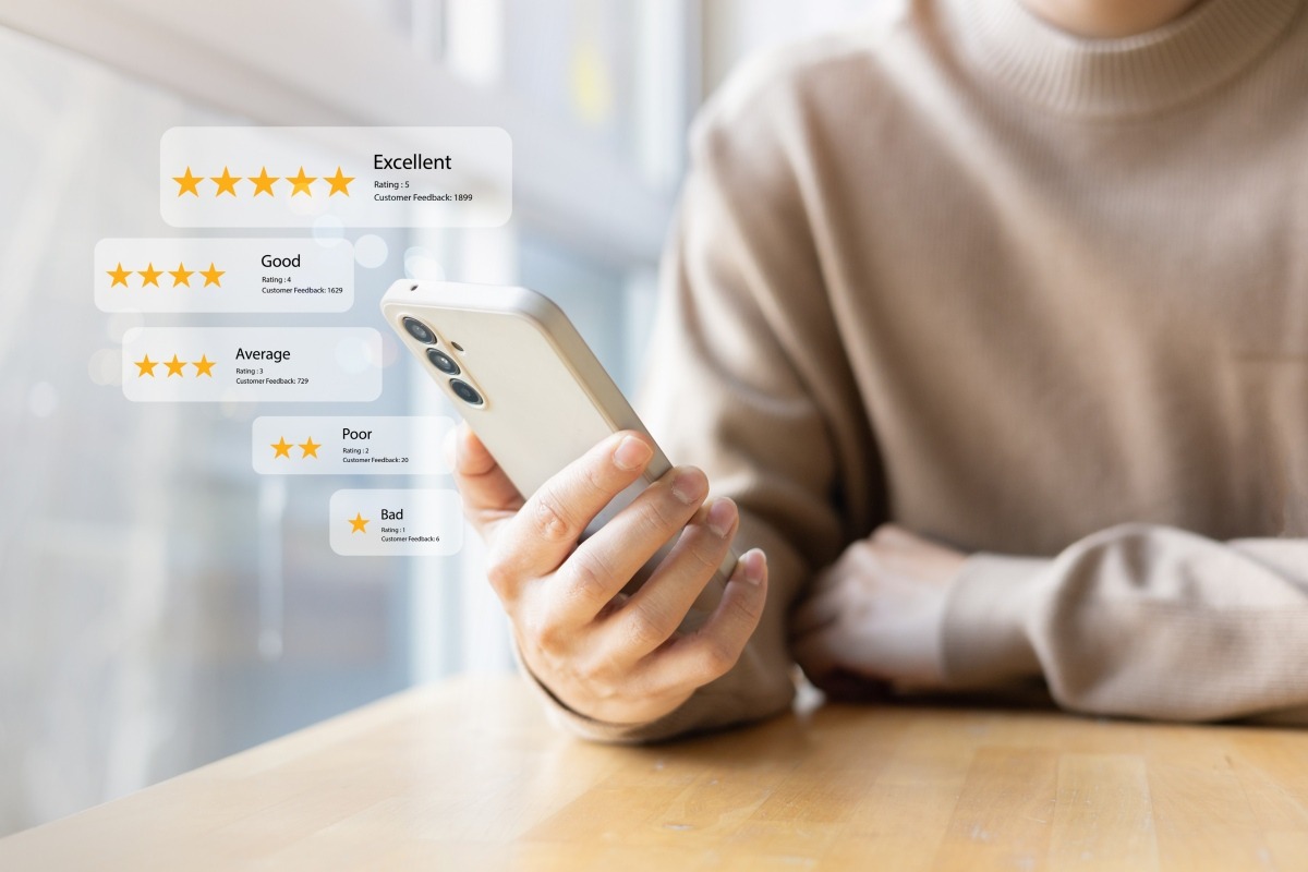 Person holding a smartphone with a review management dashboard overlay showing five rating tiers from excellent to bad, each with a star count and feedback total.