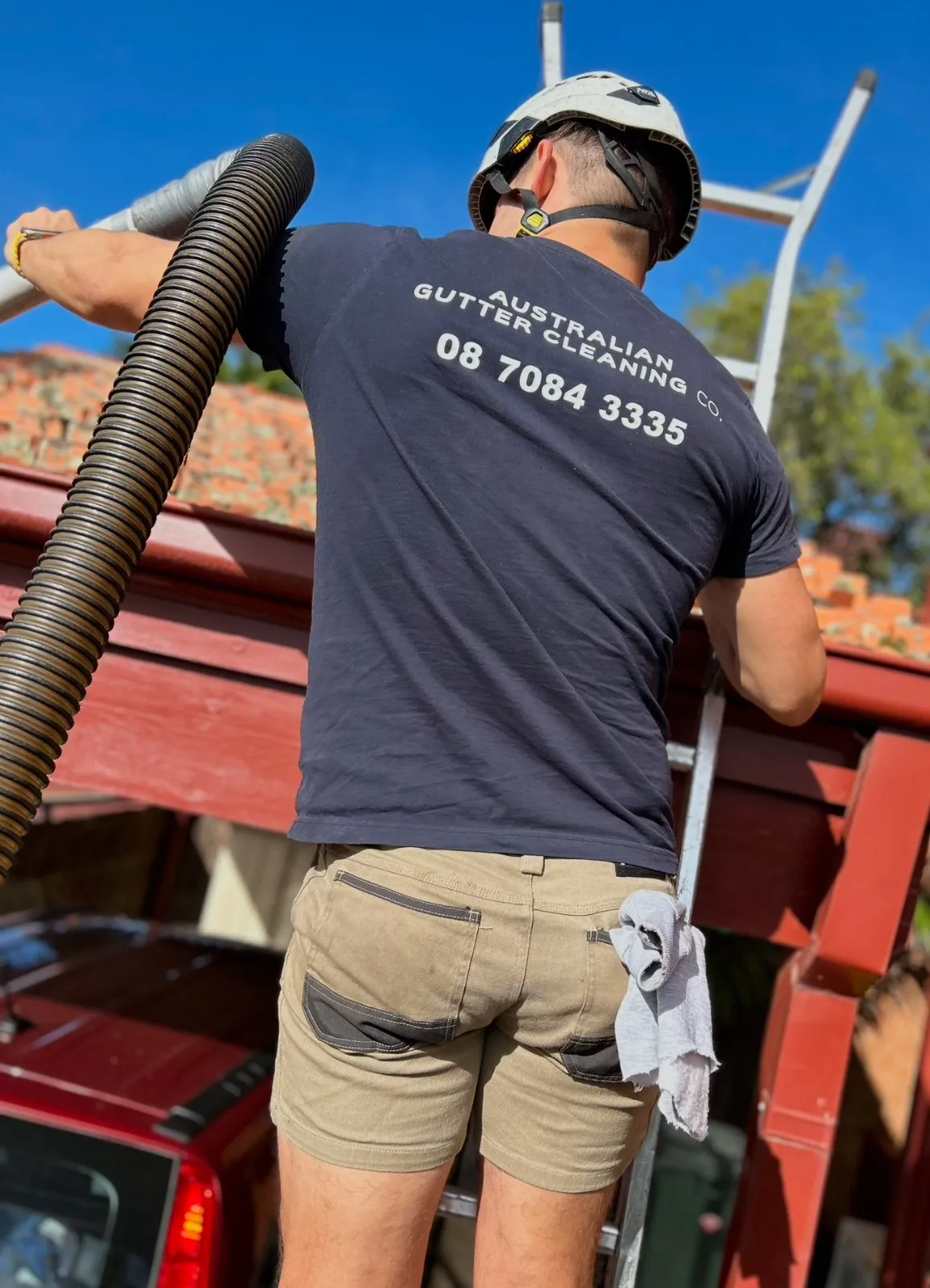 An AGCCO team member handling an industrial vacuum hose beside the service truck.