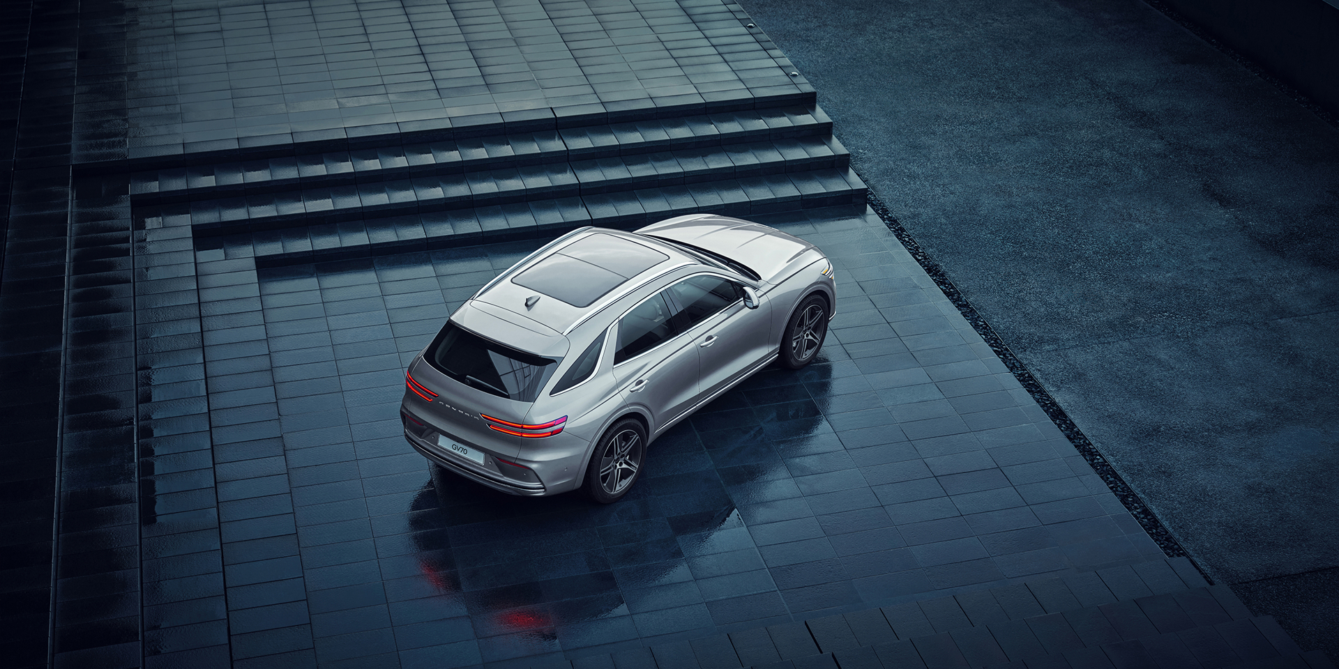 Above three quarter side view of white Electrified GV70 charging on street