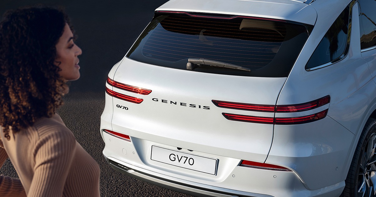 Femme debout derrière le Genesis GV70 Électrifié