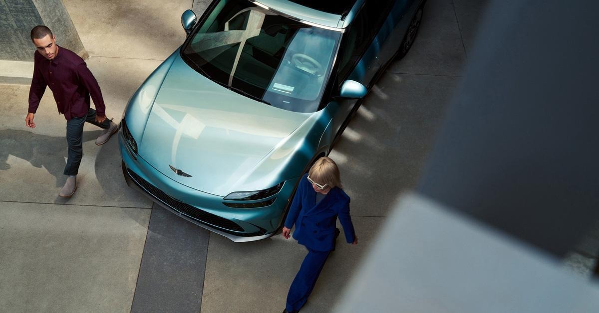 Homme et femme marchant à côté d'une Genesis GV60