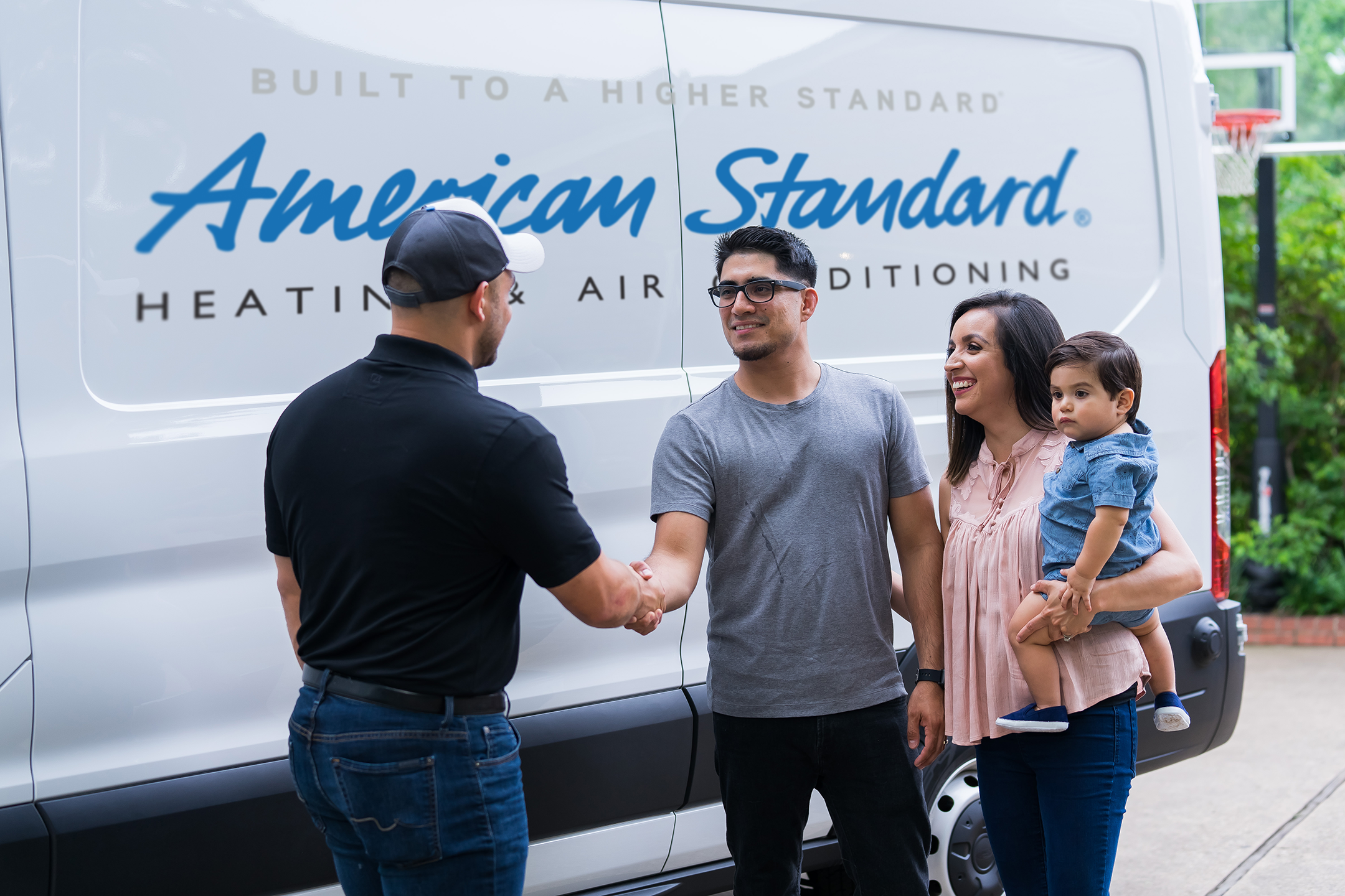 An American Standard technician greets a family after installation of a new heating system by Preferred Air.