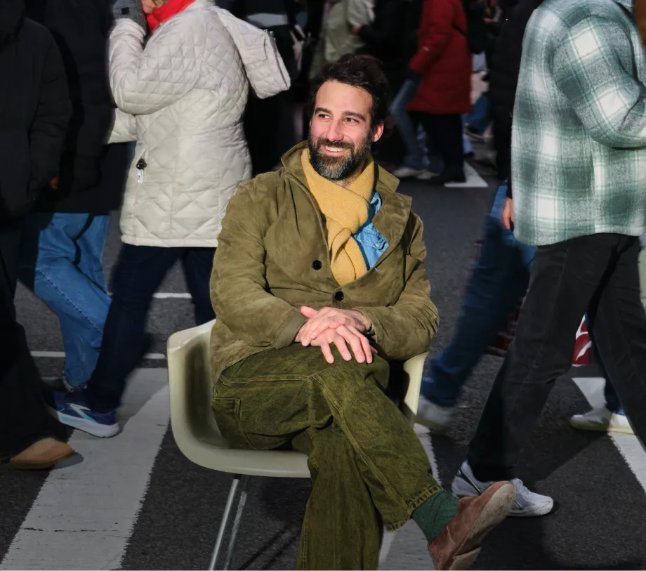 Mikey Ashmore, Sabah Owner, sitting in a chair cross legged in the middle of a busy crosswalk.