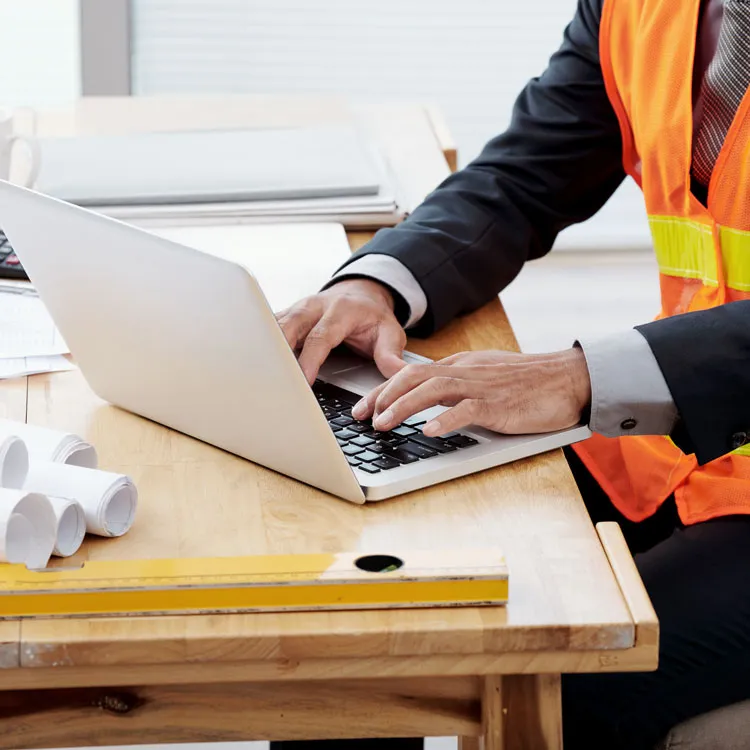 Construction worker examining weather data trends on his laptop