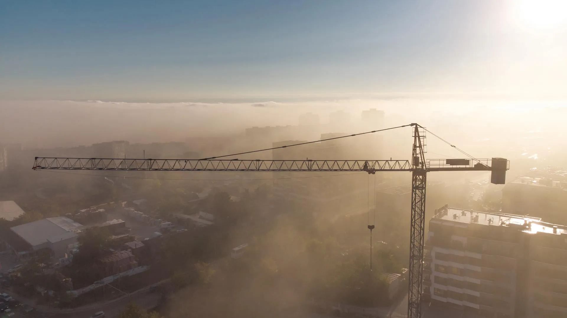 Tower cranes over a construction site with clear skies and dew in the air