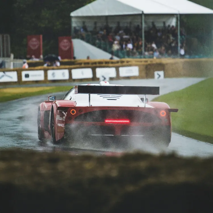 Carro de corrida numa pista de corrida com rastos de água da precipitação