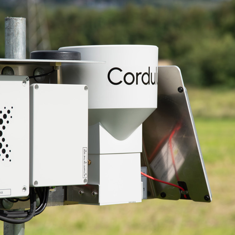 Close-up of Cordulus branded white weather monitoring device mounted outdoors on a metal pole.