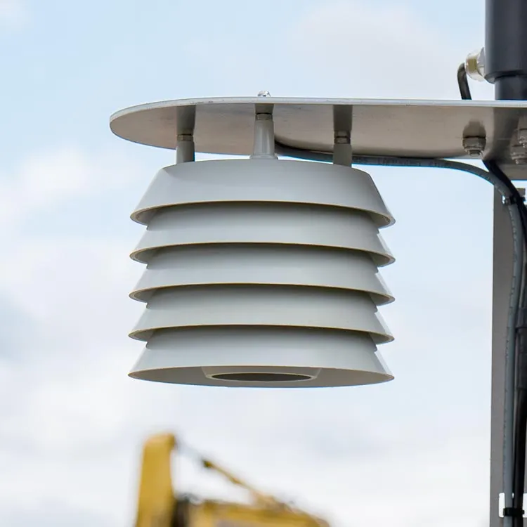Close-up of a white multi-layered air sensor from cordulus mounted outdoors against a partly cloudy sky.