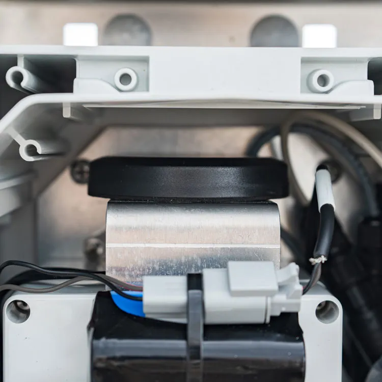 Cordulus Site GSM and Network component. A black circular part on a metallic base inside a gray plastic enclosure with connected wires and a gray connector.