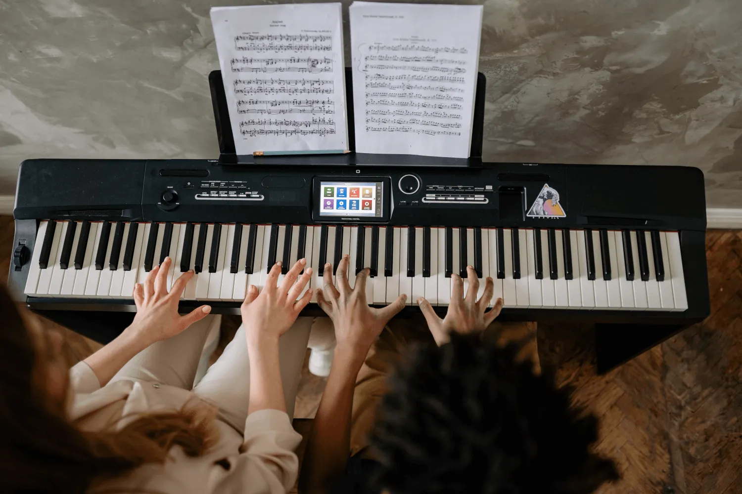 piano keys played by two sets of hands
