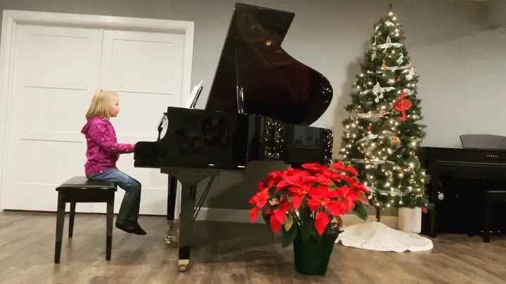 student at piano with christmas tree