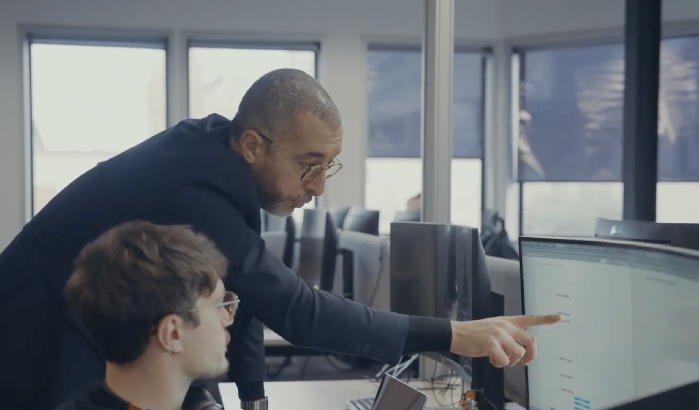 Consultant IT Systèmes montrant un tableau de supervision à un collègue