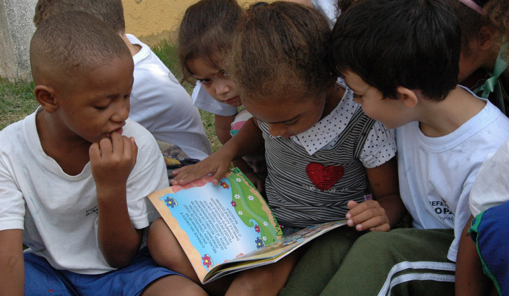 Crianças lendo livro durante a Semana Municipal de Incentivo e Orientação ao Estudo e à Leitura