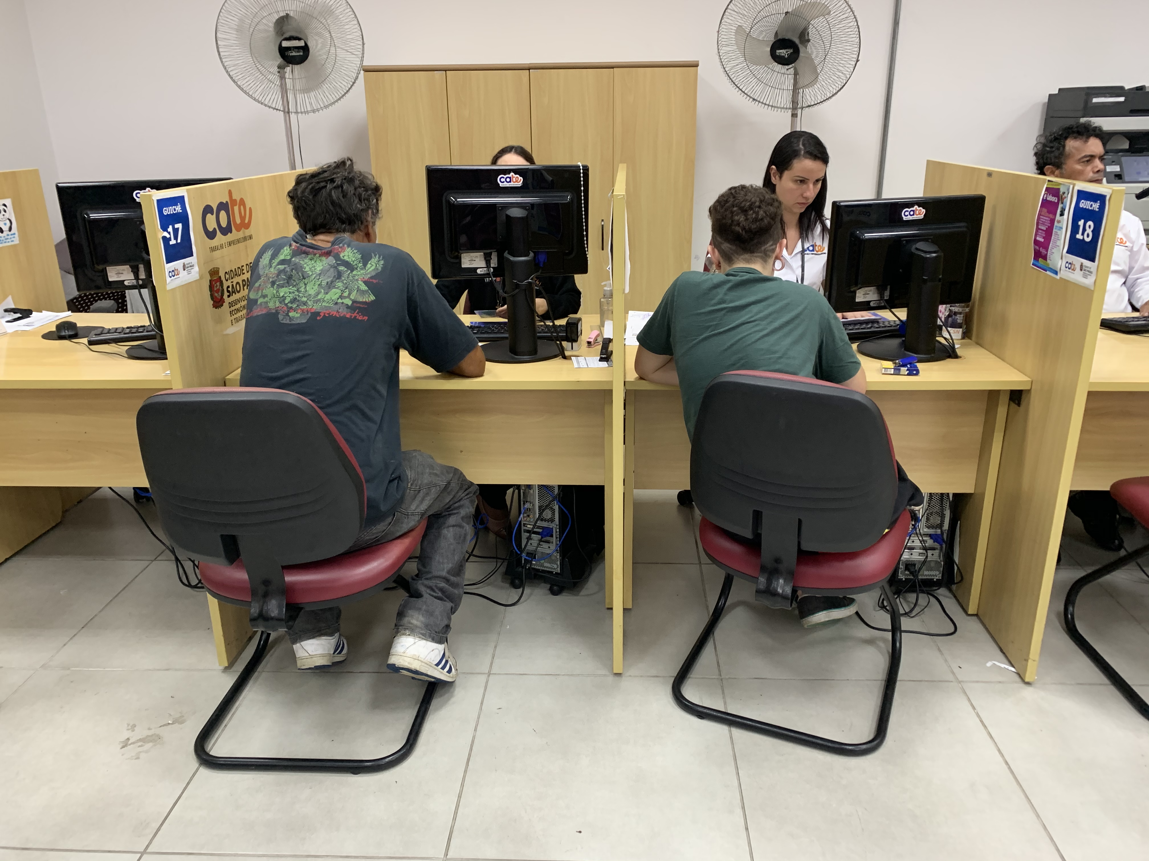 foto da recepção de uma das unidades do Cat, nela estão dois homens sendo atendidos por duas mulheres. 