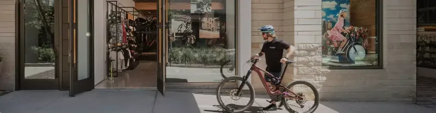 A man standing next to a bike in front of a store