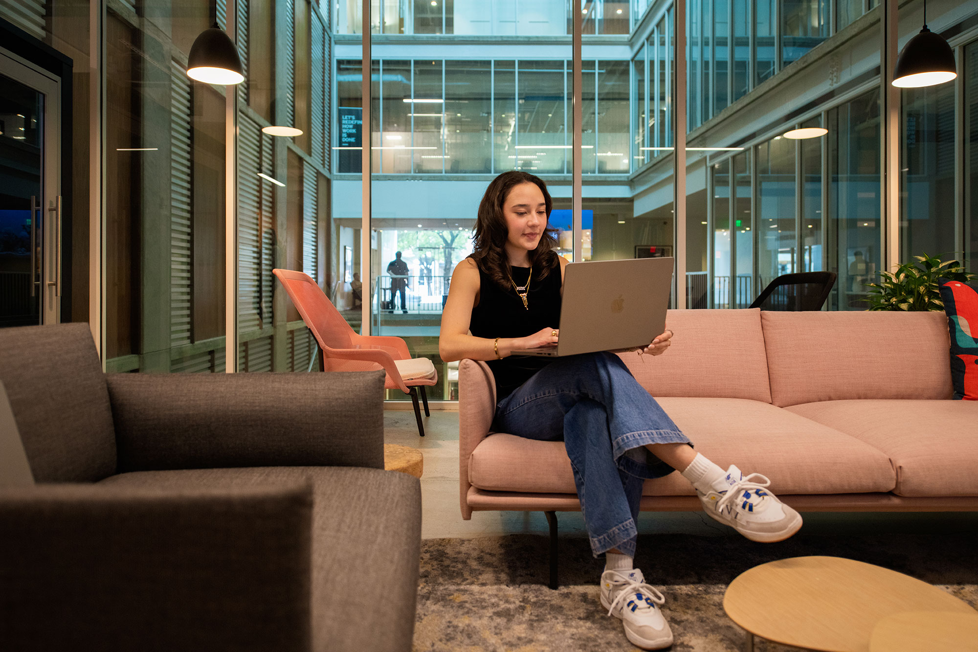 a woman sitting on a couch using a laptop computer