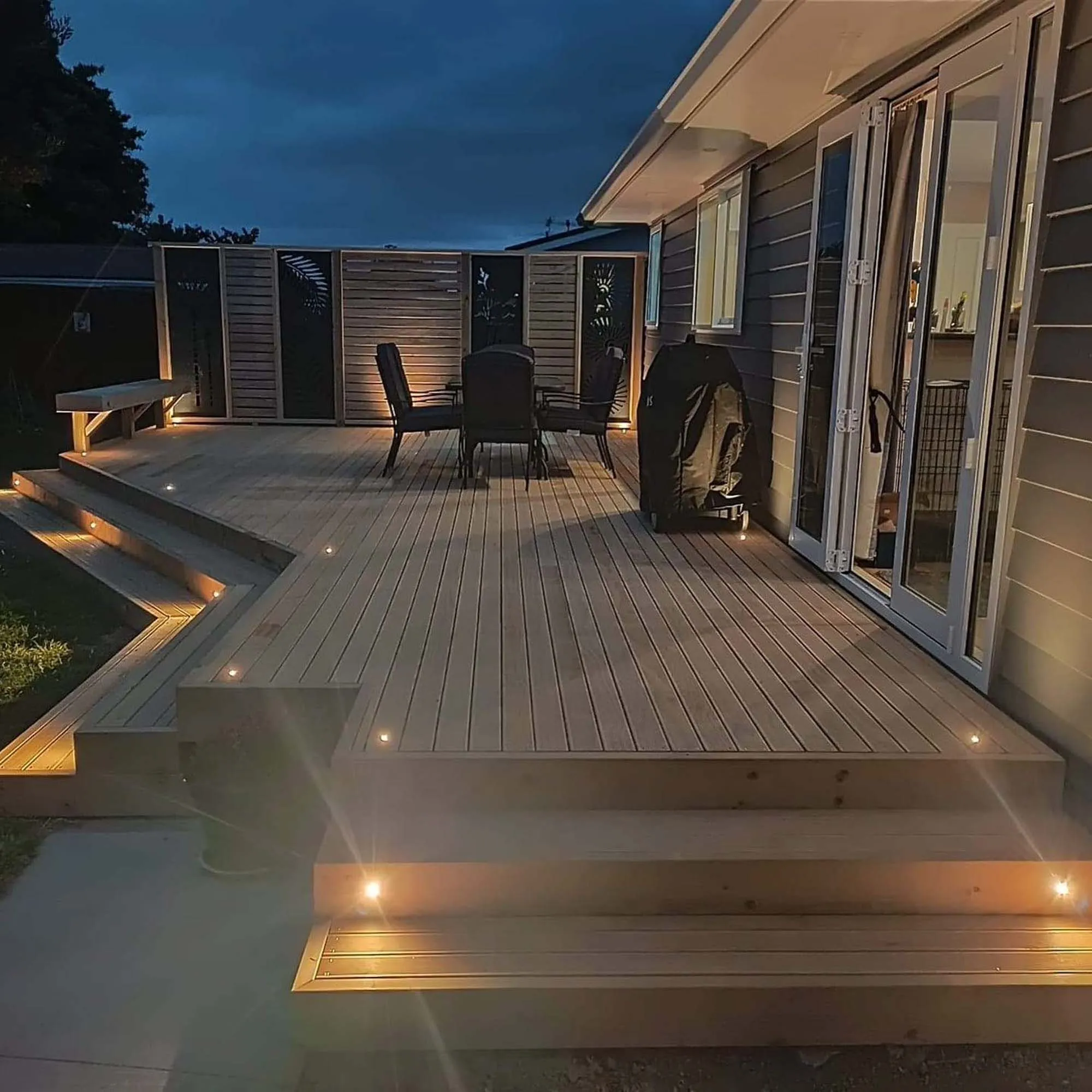 a deck with a chair and a table and a car in the background