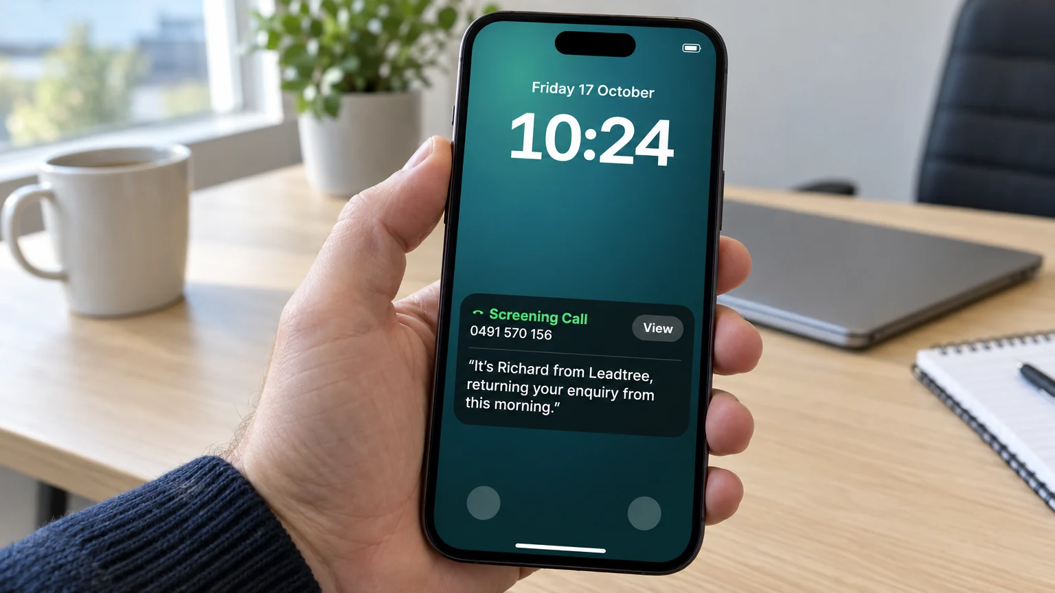 A phone held at an office desk showing a Screening Call notification on the lock screen, with the caller's answer: It's Richard from Leadtree, returning your enquiry from this morning