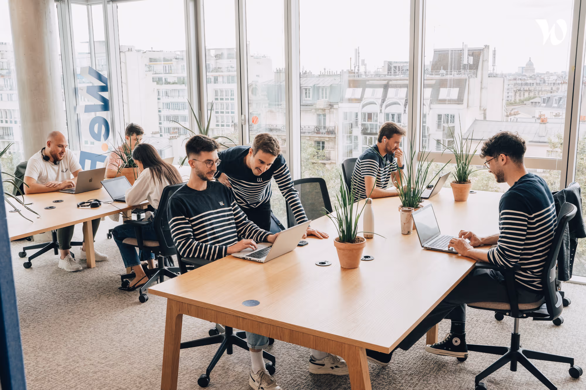 Photo d'un consultant en Product Management sur son ordinateur et deux consultants discutant autour d'un sujet.