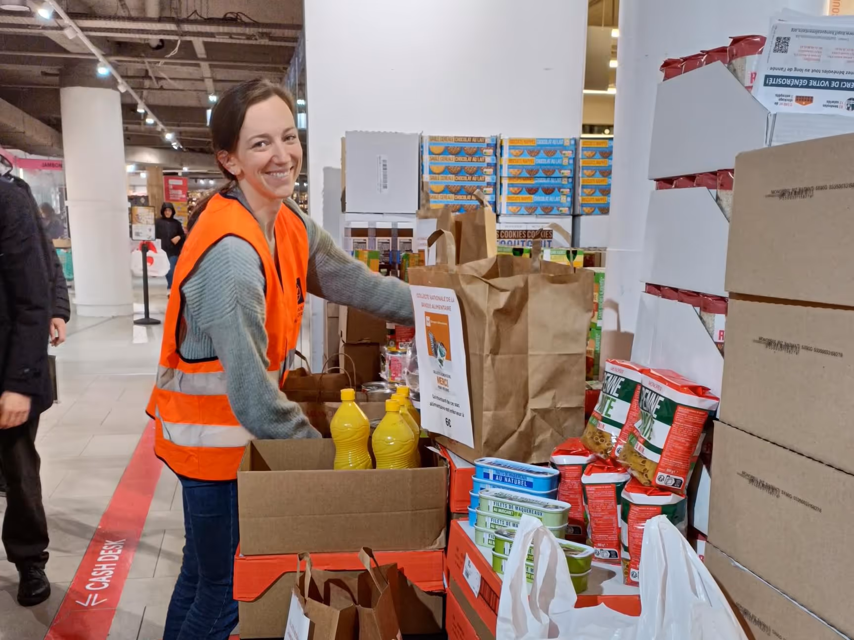 Une consultante WeFiiT souriante en gilet orange collecte pour les banques alimentaires