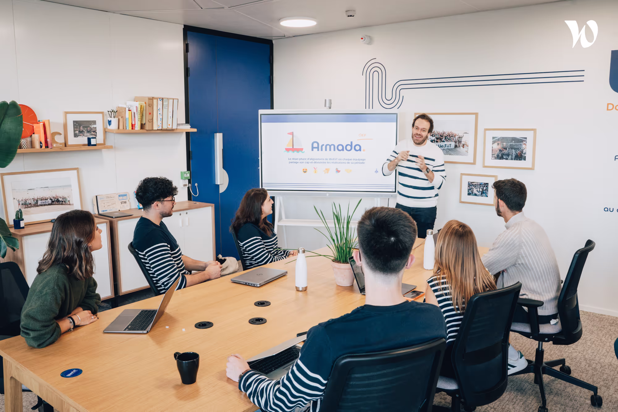 Photo d'un consultant en Product Management sur son ordinateur et deux consultants discutant autour d'un sujet.