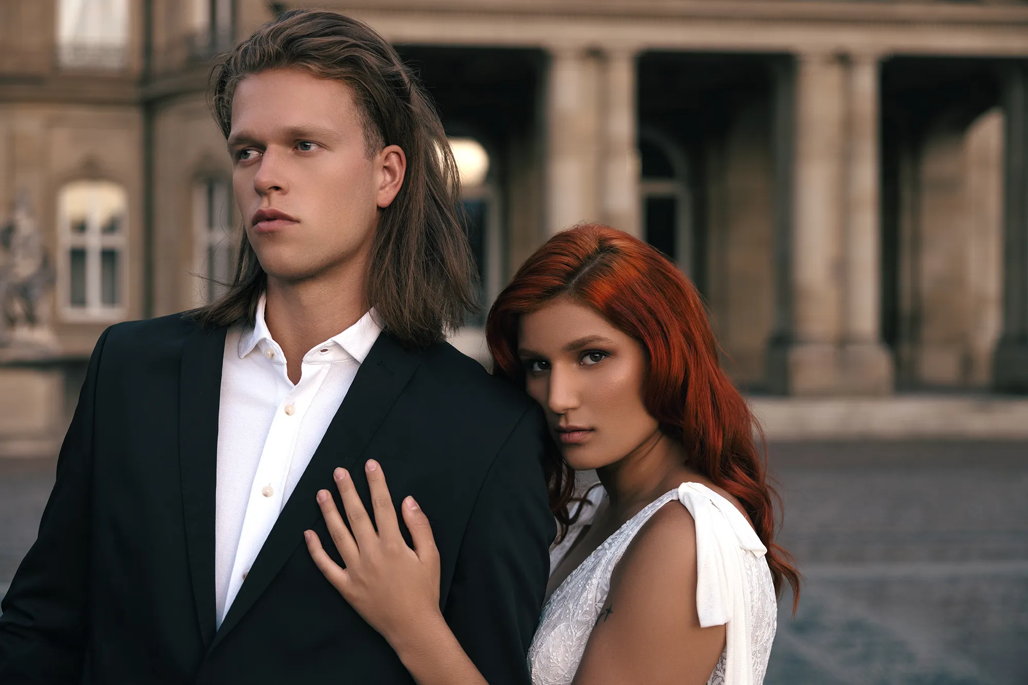 Ein Paar in festlicher Kleidung posiert vor einem majestätischen Schloss.