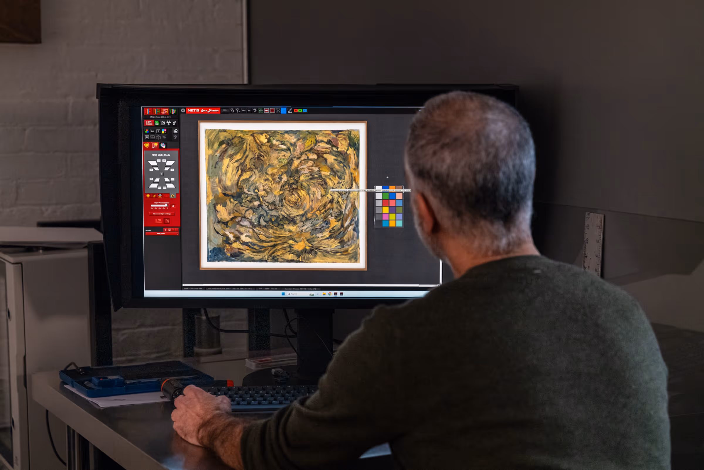 Stephen Gross at the Brooklyn Editions studio operating the Metis DRS 2020 — scanning a yellow and dark abstract painting with the color management chart visible on screen