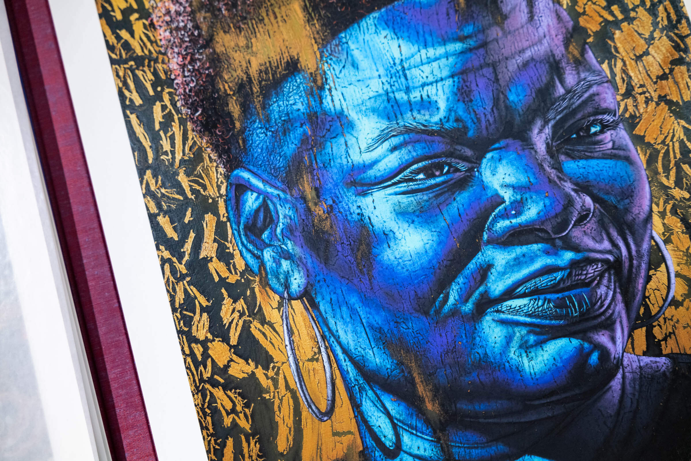 Close-up shot of Alfred Amadu Conteh's 'Reesie', which shows a painted portrait of a black figure in blues and violets against a textured gold background