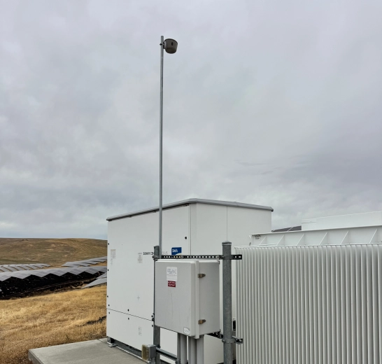 Torch sensor on a solar-powered mast overlooking a solar farm