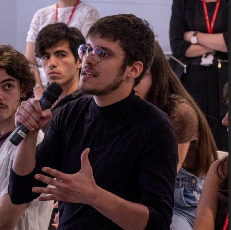 Me, Gabriel, with a microphone, asking a question in a panel.