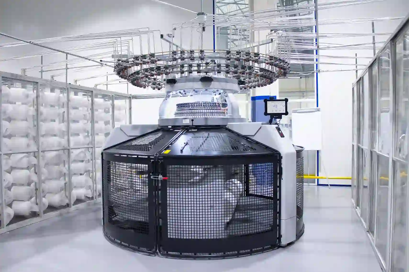 Circular industrial knitting machine inside a clean, large textile factory.