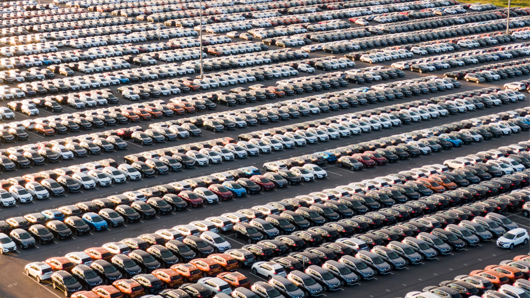 An aerial view of a car dealership parking lot with hundreds vehicles